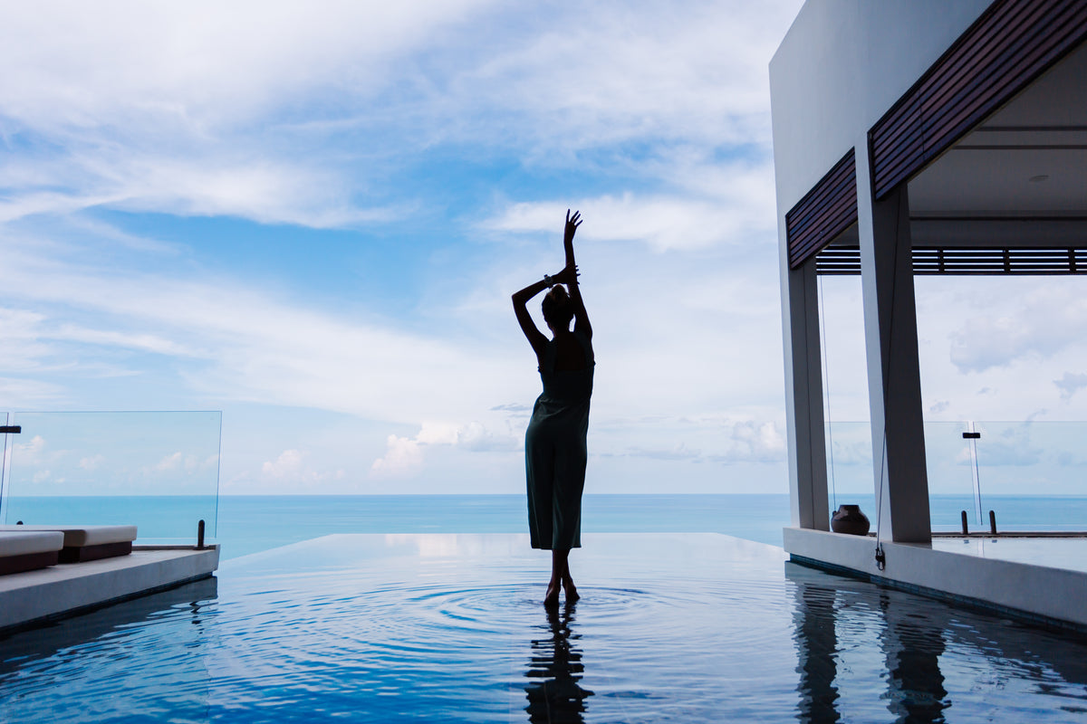 Luxvivendi Longevity – silhouette of a woman in an infinity pool of a villa by the sea